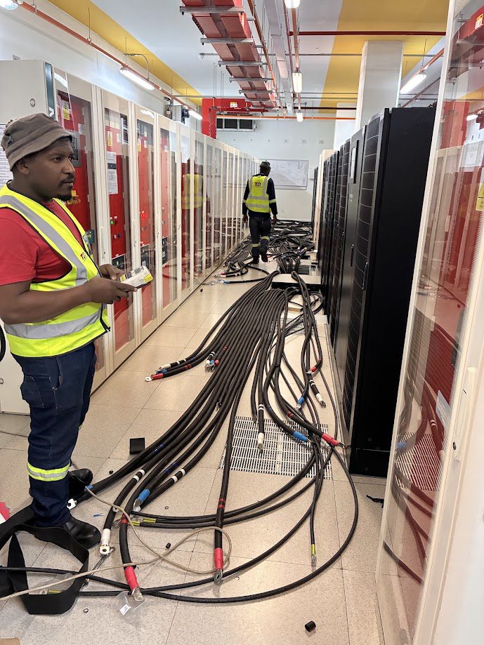 Technician pulling LV cable in a live data hall